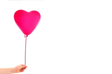 Kadın eli kırmızı kauçuk, şişme kalp şeklinde balon tutuyor. Aşk, ilişki, sevgililer günü ve doğum günü kutlaması konsepti. Stüdyo görüntüsü boş kopya alanı olan bulanık bir arkaplan üzerinde