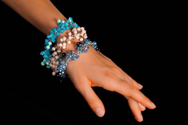 Güzel bir el yapımı mücevher bileziği. Renkli parlak boncuklar ve nötr manikürlü gevşek bir kadın bileği. Moda ve el işi aksesuarları. Yumuşak seçici odaklı yakın plan