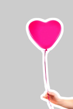 Kadın eli pembe kauçuk, şişme kalp şeklinde balon tutuyor. Aşk, ilişki, sevgililer günü ve doğum günü kutlaması konsepti. Boş kopya alanı olan dergi tarzı moda kolajı