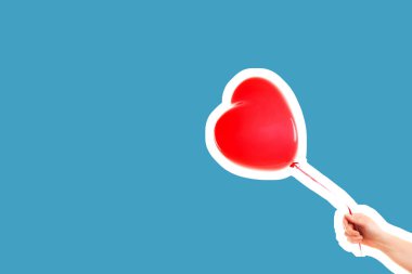 Kadın eli kırmızı kauçuk, şişme kalp şeklinde balon tutuyor. Aşk, ilişki, sevgililer günü ve doğum günü kutlaması konsepti. Boş kopya alanı olan dergi tarzı moda kolajı