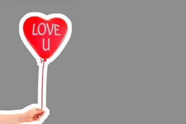 Kadın eli kırmızı kauçuk, şişme kalp şeklinde balon tutuyor. Aşk, ilişki, sevgililer günü ve doğum günü kutlaması konsepti. Boş kopya alanı olan dergi tarzı moda kolajı