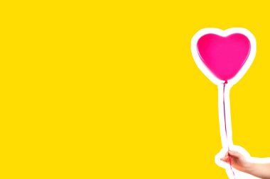 Kadın eli pembe kauçuk, şişme kalp şeklinde balon tutuyor. Aşk, ilişki, sevgililer günü ve doğum günü kutlaması konsepti. Boş kopya alanı olan dergi tarzı moda kolajı