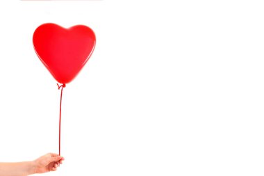 Kadın eli kırmızı kauçuk, şişme kalp şeklinde balon tutuyor. Aşk, ilişki, sevgililer günü ve doğum günü kutlaması konsepti. Stüdyo görüntüsü boş kopya alanı olan bulanık bir arkaplan üzerinde