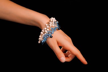 Güzel bir el yapımı mücevher bileziği. Renkli parlak boncuklar ve nötr manikürlü gevşek bir kadın bileği. Moda ve el işi aksesuarları. Yumuşak seçici odaklı yakın plan