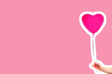Kadın eli pembe kauçuk, şişme kalp şeklinde balon tutuyor. Aşk, ilişki, sevgililer günü ve doğum günü kutlaması konsepti. Boş kopya alanı olan dergi tarzı moda kolajı