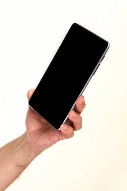 İnsan eli, avucunda boş bir krom ekran olan modern bir akıllı telefonu tutar. Teknoloji ve reklam kavramı. Ayrıntılı yakın çekim stüdyo çekimi soyut beyaz arka planda izole