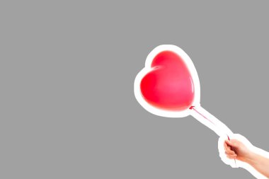 Kadın eli kırmızı kauçuk, şişme kalp şeklinde balon tutuyor. Aşk, ilişki, sevgililer günü ve doğum günü kutlaması konsepti. Boş kopya alanı olan dergi tarzı moda kolajı