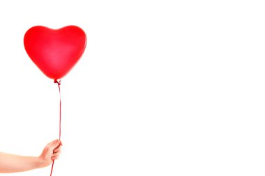 Kadın eli kırmızı kauçuk, şişme kalp şeklinde balon tutuyor. Aşk, ilişki, sevgililer günü ve doğum günü kutlaması konsepti. Stüdyo görüntüsü boş kopya alanı olan bulanık bir arkaplan üzerinde