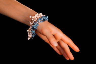 Güzel bir el yapımı mücevher bileziği. Renkli parlak boncuklar ve nötr manikürlü gevşek bir kadın bileği. Moda ve el işi aksesuarları. Yumuşak seçici odaklı yakın plan