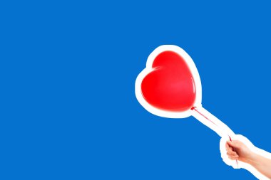 Kadın eli kırmızı kauçuk, şişme kalp şeklinde balon tutuyor. Aşk, ilişki, sevgililer günü ve doğum günü kutlaması konsepti. Boş kopya alanı olan dergi tarzı moda kolajı