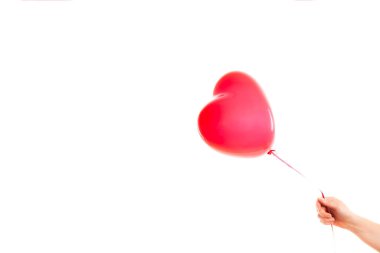 Kadın eli kırmızı kauçuk, şişme kalp şeklinde balon tutuyor. Aşk, ilişki, sevgililer günü ve doğum günü kutlaması konsepti. Stüdyo görüntüsü boş kopya alanı olan bulanık bir arkaplan üzerinde