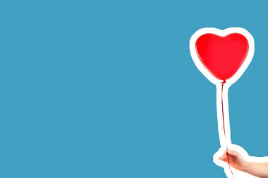 Kadın eli kırmızı kauçuk, şişme kalp şeklinde balon tutuyor. Aşk, ilişki, sevgililer günü ve doğum günü kutlaması konsepti. Boş kopya alanı olan dergi tarzı moda kolajı