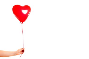 Kadın eli kırmızı kauçuk, şişme kalp şeklinde balon tutuyor. Aşk, ilişki, sevgililer günü ve doğum günü kutlaması konsepti. Stüdyo görüntüsü boş kopya alanı olan bulanık bir arkaplan üzerinde