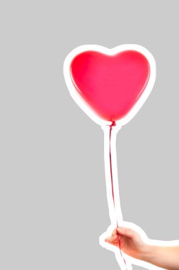 Kadın eli kırmızı kauçuk, şişme kalp şeklinde balon tutuyor. Aşk, ilişki, sevgililer günü ve doğum günü kutlaması konsepti. Boş kopya alanı olan dergi tarzı moda kolajı
