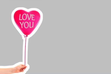 Kadın eli kırmızı kauçuk, şişme kalp şeklinde balon tutuyor. Aşk, ilişki, sevgililer günü ve doğum günü kutlaması konsepti. Boş kopya alanı olan dergi tarzı moda kolajı