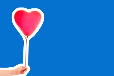 Kadın eli kırmızı kauçuk, şişme kalp şeklinde balon tutuyor. Aşk, ilişki, sevgililer günü ve doğum günü kutlaması konsepti. Boş kopya alanı olan dergi tarzı moda kolajı