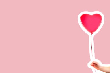 Kadın eli kırmızı kauçuk, şişme kalp şeklinde balon tutuyor. Aşk, ilişki, sevgililer günü ve doğum günü kutlaması konsepti. Boş kopya alanı olan dergi tarzı moda kolajı