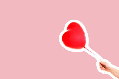 Kadın eli kırmızı kauçuk, şişme kalp şeklinde balon tutuyor. Aşk, ilişki, sevgililer günü ve doğum günü kutlaması konsepti. Boş kopya alanı olan dergi tarzı moda kolajı