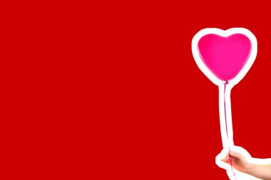 Kadın eli pembe kauçuk, şişme kalp şeklinde balon tutuyor. Aşk, ilişki, sevgililer günü ve doğum günü kutlaması konsepti. Boş kopya alanı olan dergi tarzı moda kolajı