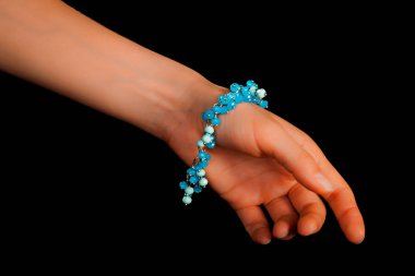 Güzel bir el yapımı mücevher bileziği. Renkli parlak boncuklar ve nötr manikürlü gevşek bir kadın bileği. Moda ve el işi aksesuarları. Yumuşak seçici odaklı yakın plan