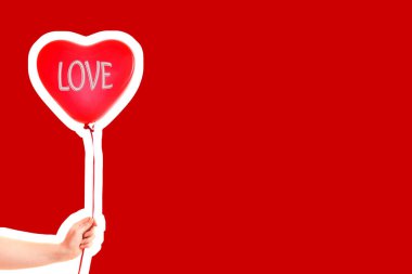 Kadın eli kırmızı kauçuk, şişme kalp şeklinde balon tutuyor. Aşk, ilişki, sevgililer günü ve doğum günü kutlaması konsepti. Boş kopya alanı olan dergi tarzı moda kolajı