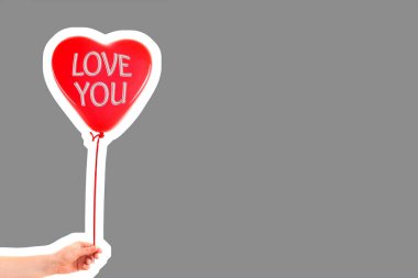 Kadın eli kırmızı kauçuk, şişme kalp şeklinde balon tutuyor. Aşk, ilişki, sevgililer günü ve doğum günü kutlaması konsepti. Boş kopya alanı olan dergi tarzı moda kolajı