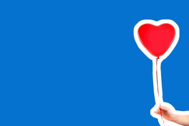 Kadın eli kırmızı kauçuk, şişme kalp şeklinde balon tutuyor. Aşk, ilişki, sevgililer günü ve doğum günü kutlaması konsepti. Boş kopya alanı olan dergi tarzı moda kolajı