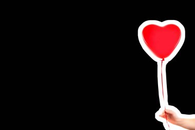 Kadın eli kırmızı kauçuk, şişme kalp şeklinde balon tutuyor. Aşk, ilişki, sevgililer günü ve doğum günü kutlaması konsepti. Boş kopya alanı olan dergi tarzı moda kolajı