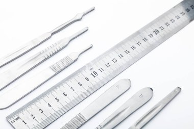 Çelik cerrahi aletler ve laboratuvar ekipmanları beyaz arka planda izole edilmiş. Profesyonel klinik aletleri. Tıbbi, cerrahi, ambulans ve veteriner konsepti. Yumuşak seçici odaklı yakın plan