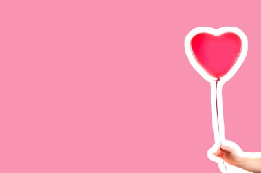 Kadın eli kırmızı kauçuk, şişme kalp şeklinde balon tutuyor. Aşk, ilişki, sevgililer günü ve doğum günü kutlaması konsepti. Boş kopya alanı olan dergi tarzı moda kolajı
