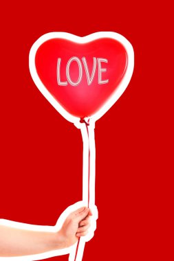 Kadın eli kırmızı kauçuk, şişme kalp şeklinde balon tutuyor. Aşk, ilişki, sevgililer günü ve doğum günü kutlaması konsepti. Boş kopya alanı olan dergi tarzı moda kolajı