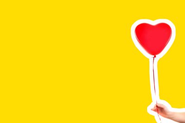 Kadın eli kırmızı kauçuk, şişme kalp şeklinde balon tutuyor. Aşk, ilişki, sevgililer günü ve doğum günü kutlaması konsepti. Boş kopya alanı olan dergi tarzı moda kolajı