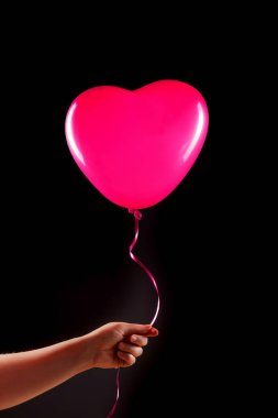 Kadın eli pembe kauçuk, şişme kalp şeklinde balon tutuyor. Aşk, ilişki, sevgililer günü ve doğum günü kutlaması konsepti. Stüdyo görüntüsü boş kopya alanı olan bulanık bir arkaplan üzerinde