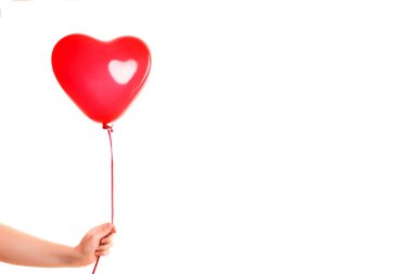 Kadın eli kırmızı kauçuk, şişme kalp şeklinde balon tutuyor. Aşk, ilişki, sevgililer günü ve doğum günü kutlaması konsepti. Stüdyo görüntüsü boş kopya alanı olan bulanık bir arkaplan üzerinde