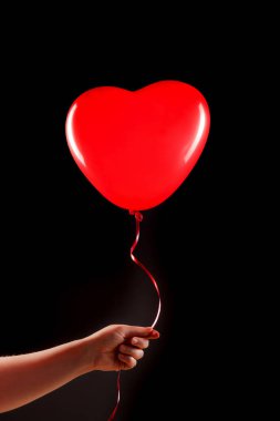 Kadın eli kırmızı kauçuk, şişme kalp şeklinde balon tutuyor. Aşk, ilişki, sevgililer günü ve doğum günü kutlaması konsepti. Stüdyo görüntüsü boş kopya alanı olan bulanık bir arkaplan üzerinde