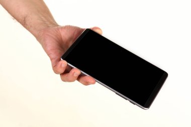 İnsan eli, avucunda boş bir krom ekran olan modern bir akıllı telefonu tutar. Teknoloji ve reklam kavramı. Ayrıntılı yakın çekim stüdyo çekimi soyut beyaz arka planda izole
