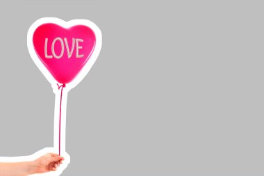 Kadın eli kırmızı kauçuk, şişme kalp şeklinde balon tutuyor. Aşk, ilişki, sevgililer günü ve doğum günü kutlaması konsepti. Boş kopya alanı olan dergi tarzı moda kolajı