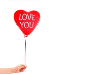 Kadın eli kırmızı kauçuk, şişme kalp şeklinde balon tutuyor. Aşk, ilişki, sevgililer günü ve doğum günü kutlaması konsepti. Stüdyo görüntüsü boş kopya alanı olan bulanık bir arkaplan üzerinde