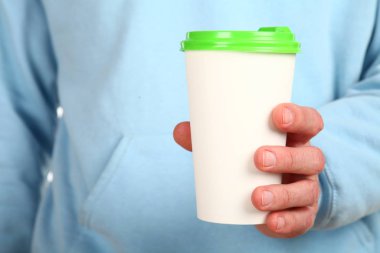 İnsan eli plastik kapaklı boş bir kahve fincanı tutar. Tek kullanımlık fincana çay ya da kahve konsepti. Metin veya logo için yeri ve yeri kopyala. Beyaz bir arkaplanda izole edilmiş
