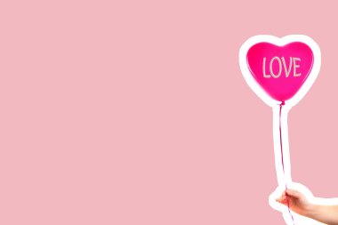 Kadın eli kırmızı kauçuk, şişme kalp şeklinde balon tutuyor. Aşk, ilişki, sevgililer günü ve doğum günü kutlaması konsepti. Boş kopya alanı olan dergi tarzı moda kolajı