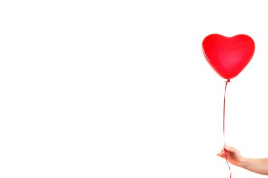 Kadın eli kırmızı kauçuk, şişme kalp şeklinde balon tutuyor. Aşk, ilişki, sevgililer günü ve doğum günü kutlaması konsepti. Stüdyo görüntüsü boş kopya alanı olan bulanık bir arkaplan üzerinde