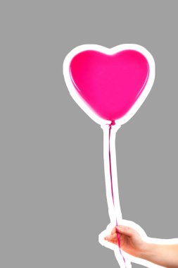 Kadın eli pembe kauçuk, şişme kalp şeklinde balon tutuyor. Aşk, ilişki, sevgililer günü ve doğum günü kutlaması konsepti. Boş kopya alanı olan dergi tarzı moda kolajı
