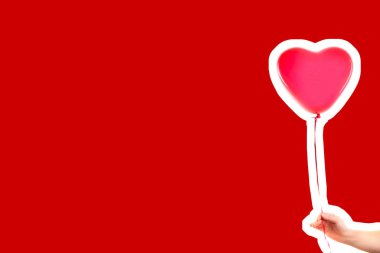 Kadın eli kırmızı kauçuk, şişme kalp şeklinde balon tutuyor. Aşk, ilişki, sevgililer günü ve doğum günü kutlaması konsepti. Boş kopya alanı olan dergi tarzı moda kolajı
