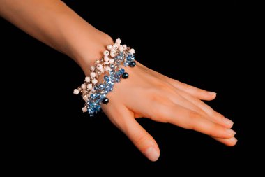 Güzel bir el yapımı mücevher bileziği. Renkli parlak boncuklar ve nötr manikürlü gevşek bir kadın bileği. Moda ve el işi aksesuarları. Yumuşak seçici odaklı yakın plan