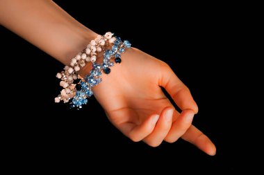 Güzel bir el yapımı mücevher bileziği. Renkli parlak boncuklar ve nötr manikürlü gevşek bir kadın bileği. Moda ve el işi aksesuarları. Yumuşak seçici odaklı yakın plan
