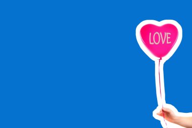 Kadın eli kırmızı kauçuk, şişme kalp şeklinde balon tutuyor. Aşk, ilişki, sevgililer günü ve doğum günü kutlaması konsepti. Boş kopya alanı olan dergi tarzı moda kolajı