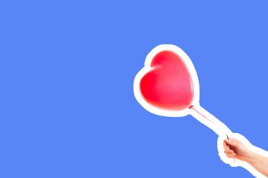 Kadın eli kırmızı kauçuk, şişme kalp şeklinde balon tutuyor. Aşk, ilişki, sevgililer günü ve doğum günü kutlaması konsepti. Boş kopya alanı olan dergi tarzı moda kolajı