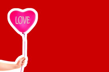 Kadın eli kırmızı kauçuk, şişme kalp şeklinde balon tutuyor. Aşk, ilişki, sevgililer günü ve doğum günü kutlaması konsepti. Boş kopya alanı olan dergi tarzı moda kolajı