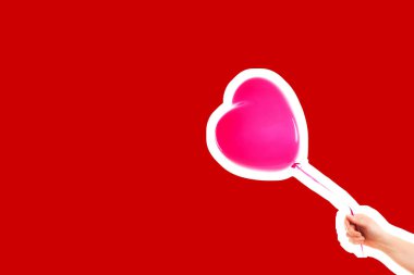 Kadın eli pembe kauçuk, şişme kalp şeklinde balon tutuyor. Aşk, ilişki, sevgililer günü ve doğum günü kutlaması konsepti. Boş kopya alanı olan dergi tarzı moda kolajı