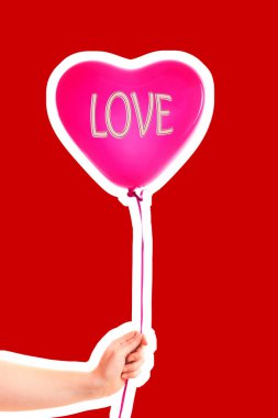 Kadın eli kırmızı kauçuk, şişme kalp şeklinde balon tutuyor. Aşk, ilişki, sevgililer günü ve doğum günü kutlaması konsepti. Boş kopya alanı olan dergi tarzı moda kolajı